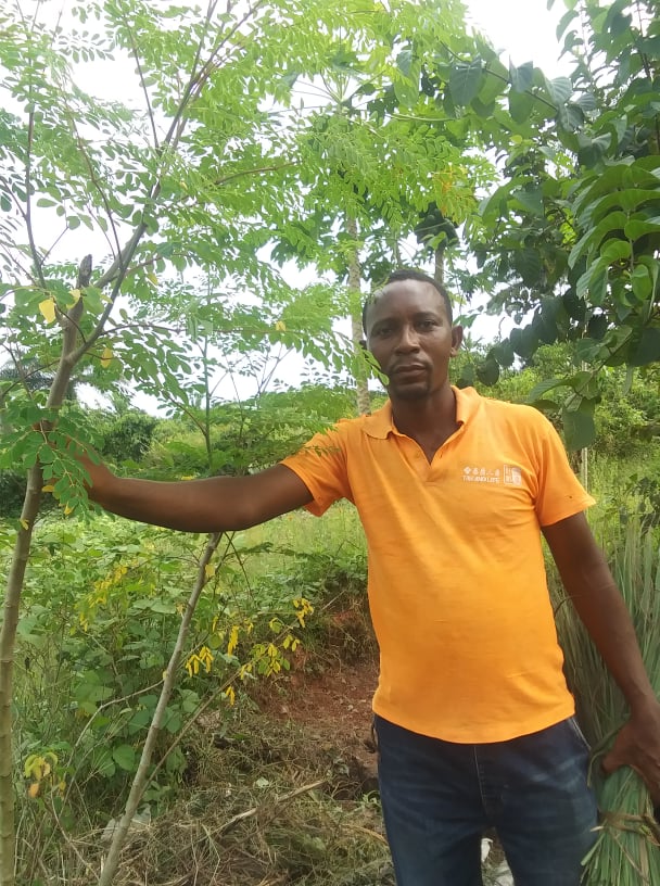 Kelvin stands by a moringa tree on the Provision of Hope Farm