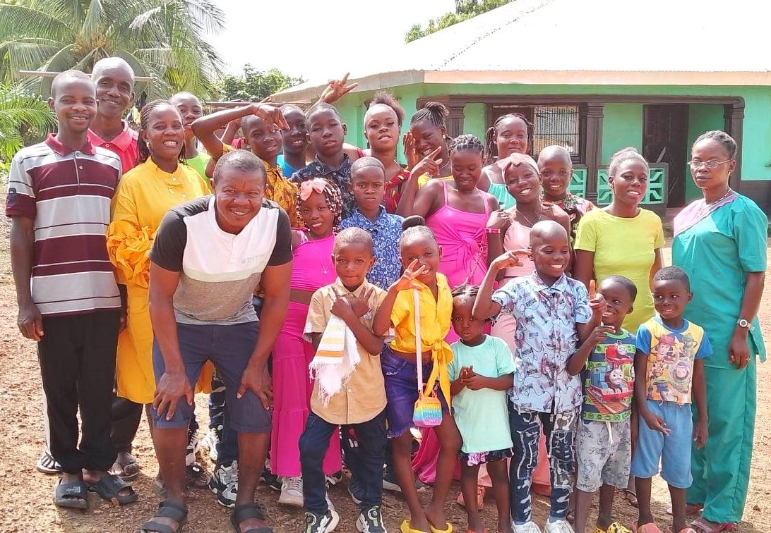 Benetta is the mother in Otis Dyega's Home. She stands on the far right. They have 14 children. Roger & Ruth Gbah with their 6 children are now part of the Dyega Family. They live close by.  Praise God for how they have become one big happy family! They are a light in their community!