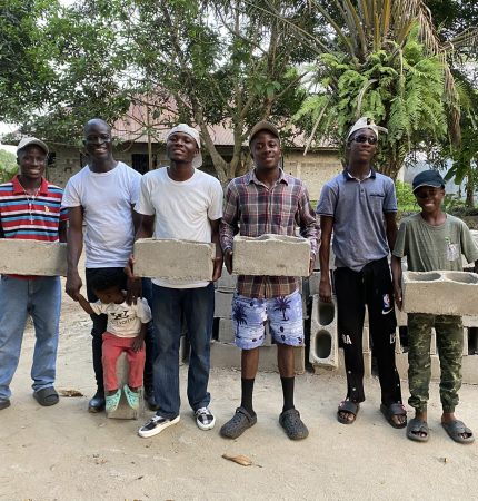 The boys are learning how to make concrete bricks